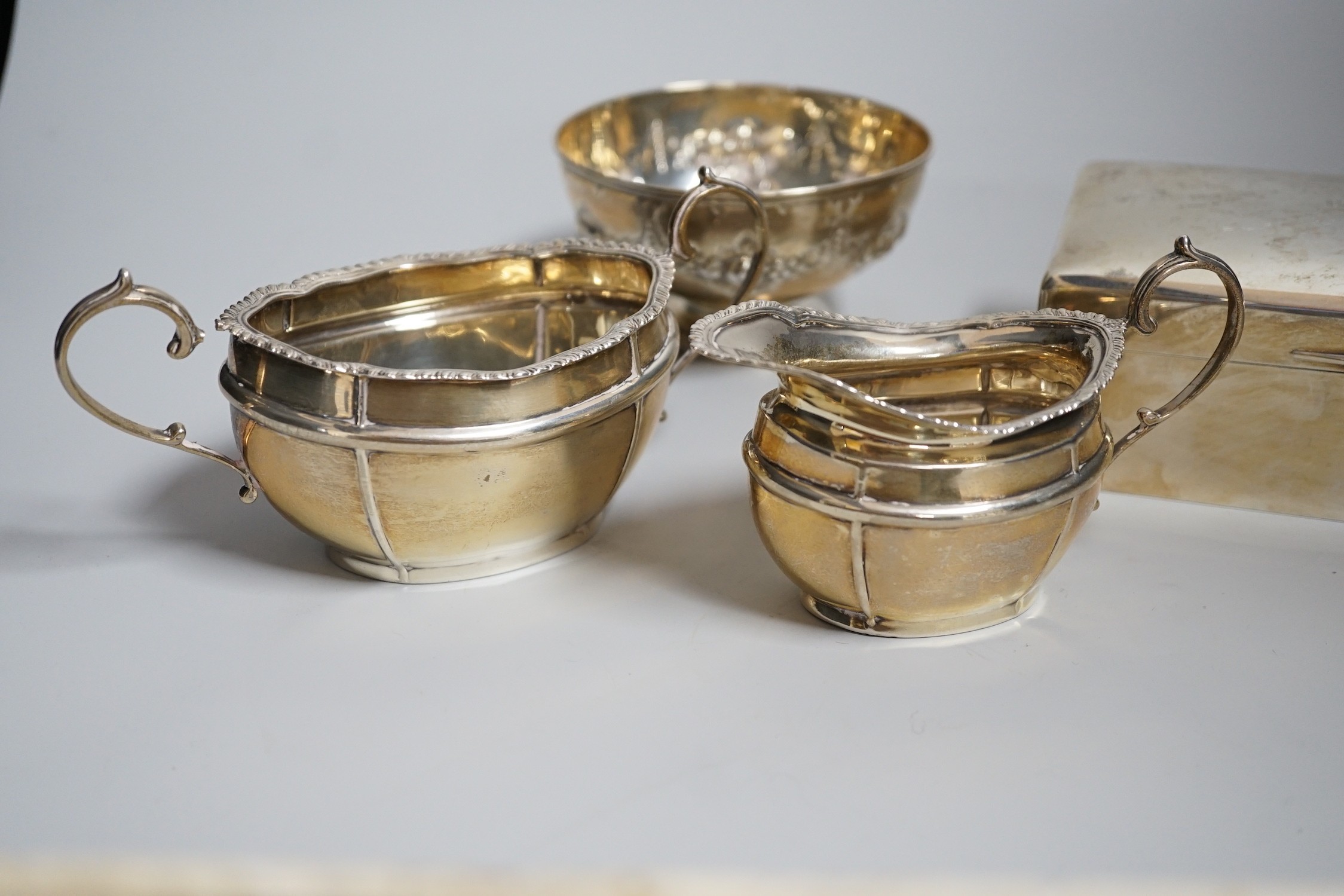 A George V silver milk jug and sugar bowl, London, 1917, a silver mounted cigarette box and a small silver bowl.